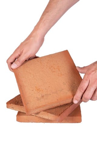 Persona mostrando baldosa de barro cocido hecha a mano
