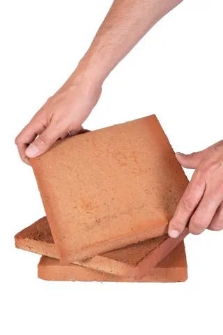 Persona mostrando baldosa de barro cocido hecha a mano